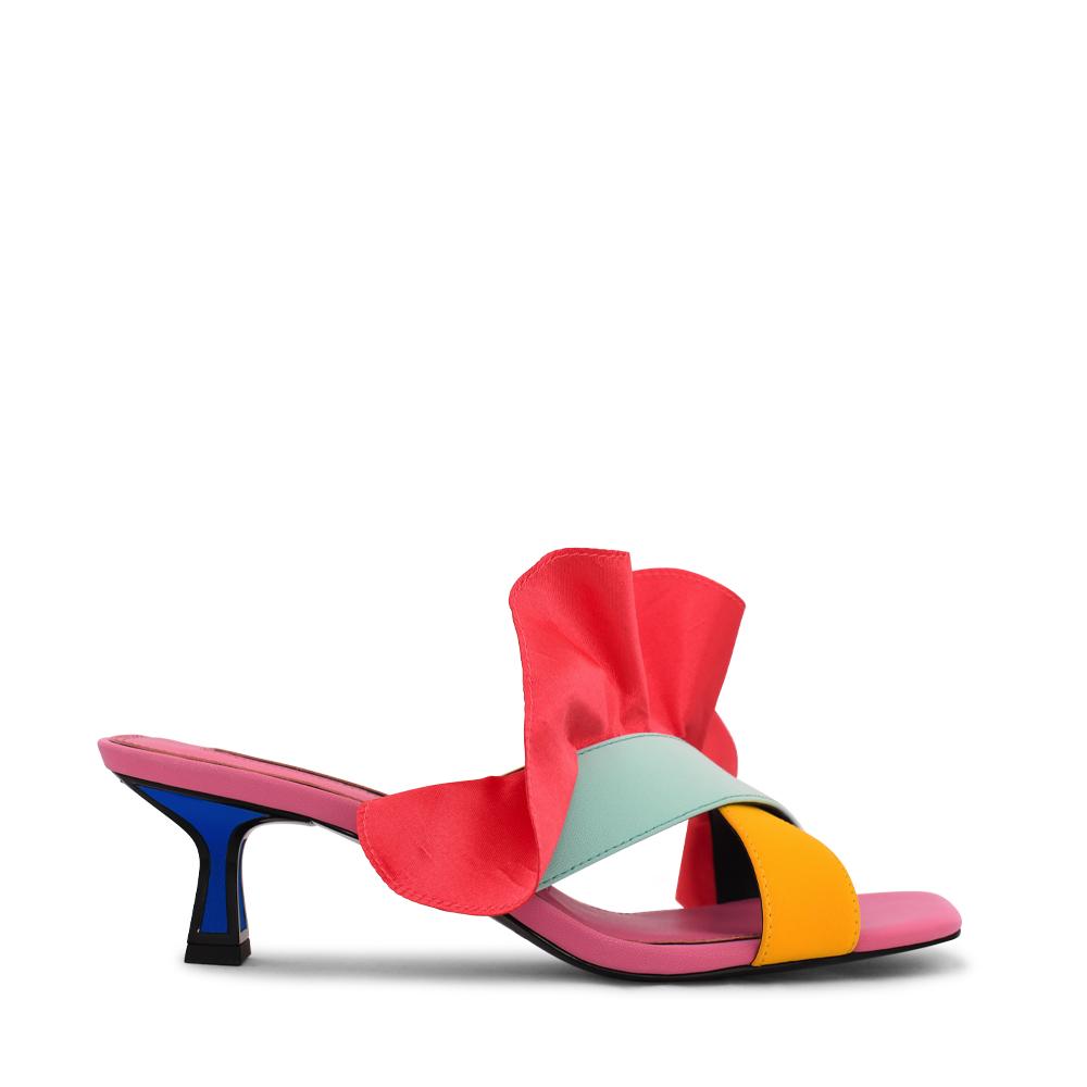 Outer side view of the kat maconie dia kitten heel. This slip on heel features a pink sole, a tiny blue heel outlined with black, two cross over straps, and a pink/red satin ruffle attached to the upper.