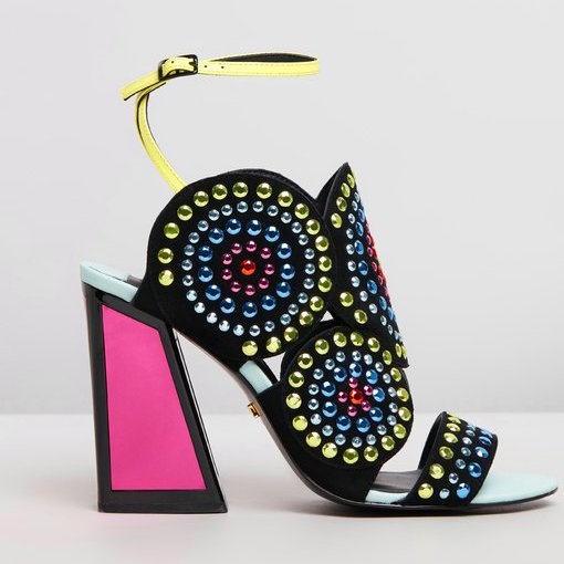 Outer side view of the kat maconie frida multibrights high heels. This shoe is black with multicolored rhinestones arranged in circles. The toe and back are open. The shoe features a yellow ankle strap and a pink high heel with a black outline. 