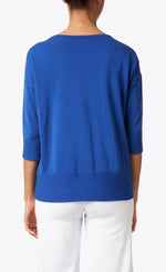 Load image into Gallery viewer, Back view of a woman wearing the royal blue easy rib pullover sweater top from Kinross. This top has 3/4 length sleeves and ribbed detailing on the bottom of the sleeves and bottom of the top.
