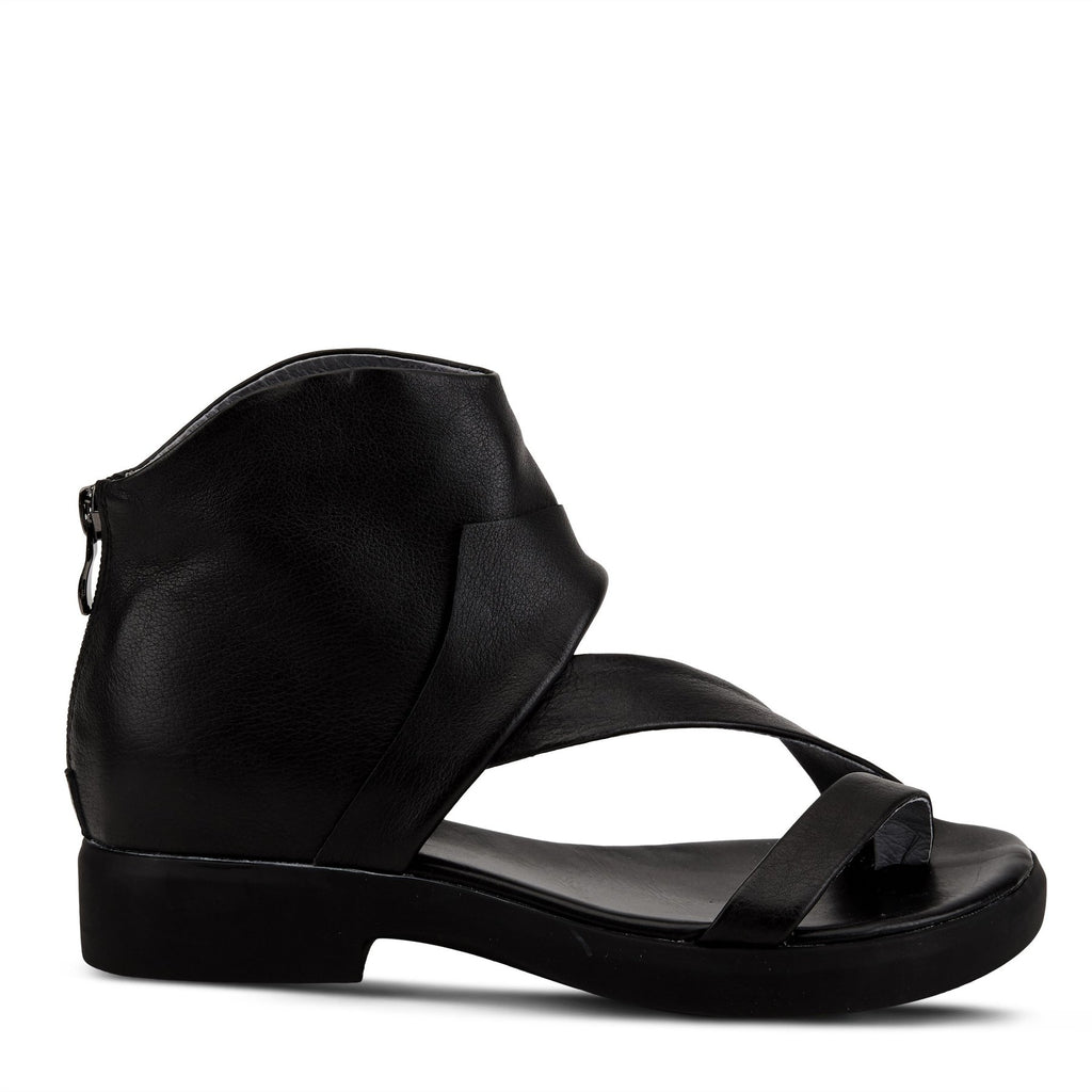 Outer side view of the l'artiste gladiator sandal in black. This sandal covers the heel and ankle with a black folded leather. The instep is covered with a strap that goes over it and another strap that goes over the toes.