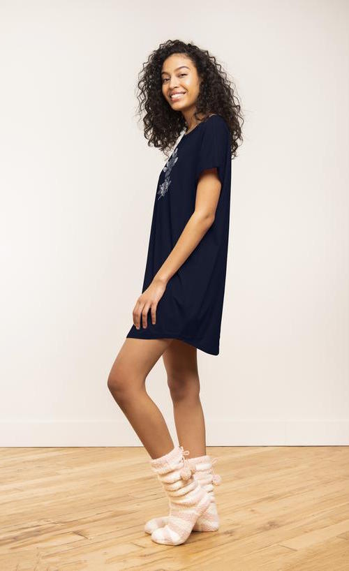 Left side view of a woman wearing the coffee shoppe t-shirt dress. This t-shirt dress is navy with a floral print.