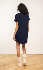 Load image into Gallery viewer, Back view of a woman wearing the coffee shoppe t-shirt dress. This short sleeve t-shirt dress is navy.
