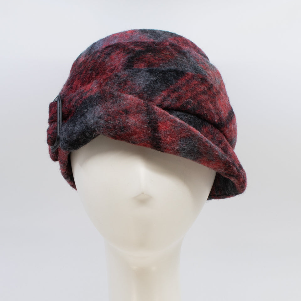 Front view of a the lillie & cohoe iconic prints lexi hat. This has has red and grey plaid and a tiered/folded crown. The right side of the hat has a decorative black buckle.