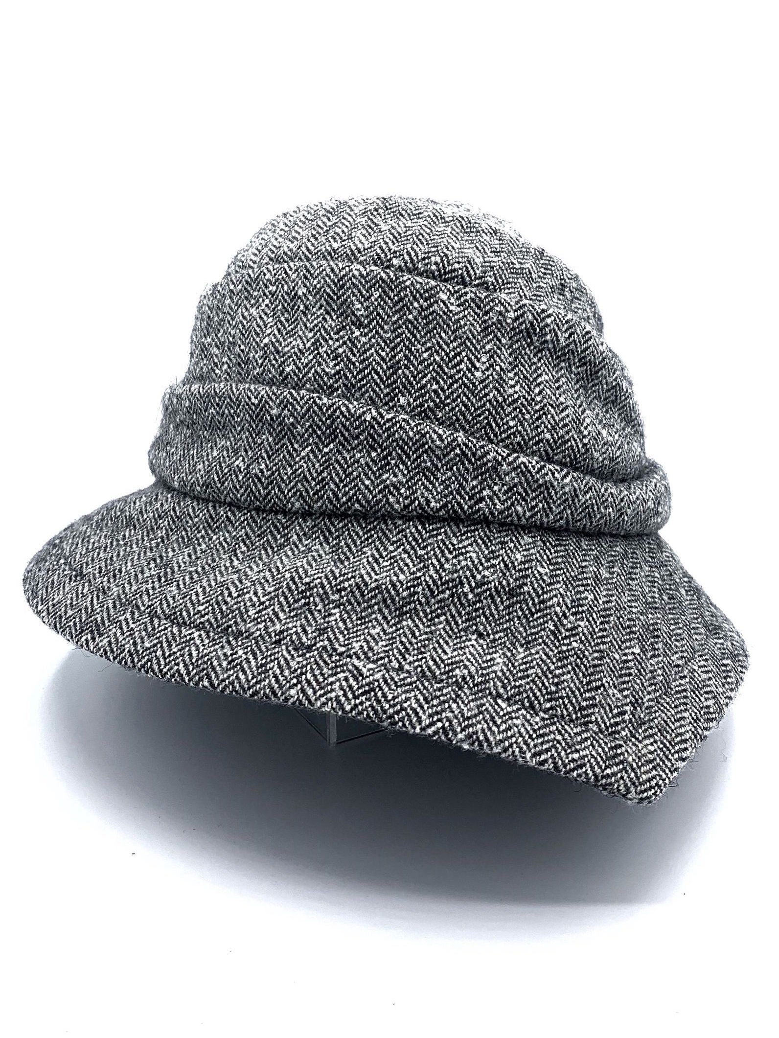 Front view of the lillie & cohoe herringbone vintage phoebe hat. This hat has an asymmetrical pointed brim, a layered crown, and a grey herringbone pattern.