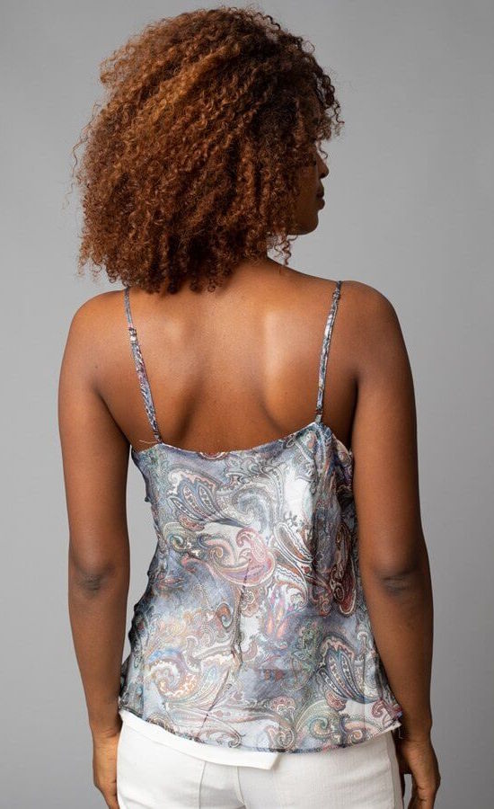 Back top half view of a woman wearing the Cowl Neck Cami from Lola & Sophie. This cami has thin straps and a soft paisley print that is primarily blue with mixes of red and other colors.