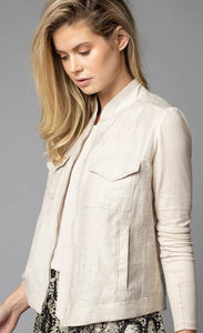 Front, top half left side view of a woman wearing the Lola & Sophie Crinkle Linen Jean Jacket. The sand colored jacket features two front, fold over breast pockets, a zipper front, a linen body, and fitted long sleeves.