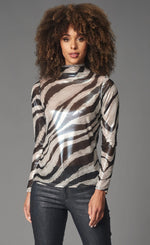 Load image into Gallery viewer, Front top half view of a woman wearing black pants and the lola &amp; Sophie foil zebra mesh turtleneck. This top has a white and silver zebra print all over it and long sleeves.
