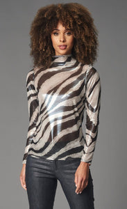 Front top half view of a woman wearing black pants and the lola & Sophie foil zebra mesh turtleneck. This top has a white and silver zebra print all over it and long sleeves.