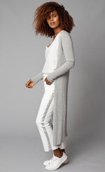 Load image into Gallery viewer, Left side, full body view of a woman with her hands in the pocket of her white pant with a grey side stipe. The woman is also wearing the lola &amp; sophie white v-neck tank under the lola &amp; sophie split back cardi. This cardigan is grey and goes down to the model&#39;s ankle. The long sleeves are fitted and ribbed.
