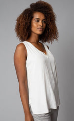 Load image into Gallery viewer, Front, right-sided view of the top half of a woman wearing the Lola &amp; Sophie V-Neck tank. This tank is eggshell colored and has a small side slit near the bottom and detailed trim around the v-neck.
