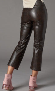 Back bottom half view of a woman wearing the lola & sophie vegan leather kick flare pant. This pant is grey colored with a subtle crocodile print, a cropped leg, and a flared out bottom.
