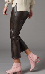 Load image into Gallery viewer, Left side bottom half view of a woman wearing the lola &amp; sophie vegan leather kick flare pant. This pant is grey colored with a subtle crocodile print, a cropped leg, and a flared out bottom.
