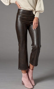 Front bottom half view of a woman wearing the lola & sophie vegan leather kick flare pant. This pant is grey colored with a subtle crocodile print, a cropped leg, and a flared out bottom.