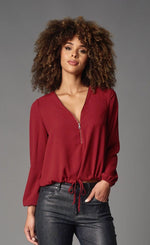 Load image into Gallery viewer, Front top half view of the Lola &amp; Sophie Zip Neck Double Georgette Top. This top is Garnet/Red colored. It has a zipper v-neck, long sleeves with elastic cuffs, and a drawstring/tie hem.
