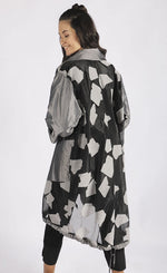 Load image into Gallery viewer, Back full body view of a woman wearing the luukaa abstract jacquard organza jacket. This mid-length jacket has a black see-through organza body with grey sleeves, a grey collar, grey pockets, and a grey abstract print.
