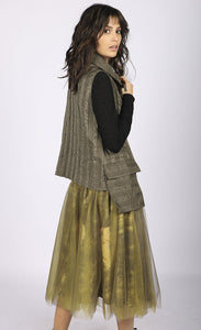 Right side full body view of a woman wearing a brown vest over a black long sleeve top. On the bottom she is wearing the luukaa floral tulle skirt in khaki. This shirt has khaki tulle and a floral lining that shows through underneath. The skirt sits below the knees.