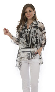 Front top half view of a woman wearing white capris and the luukaa leaf print top. This top is sheer with white and grey leaf print. The sleeves are 3/4 length, the neck is a v-neck, and the hem is short in the front and long on the sides.