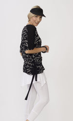 Load image into Gallery viewer, Top half, right side view of the luukaa scribble top in black. This black top has white handwriting all over it, a side adjustable belt that can be tied, and elbow length sleeves.
