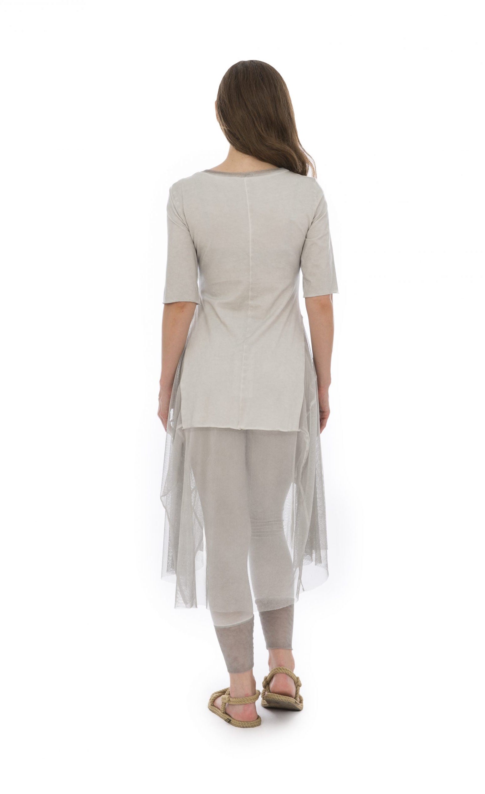 Back full body view of a woman wearing the luukaa stone leggings in the color beige. They have mesh trim on the bottom. On the top the model is wearing the luukaa tunic in beige.