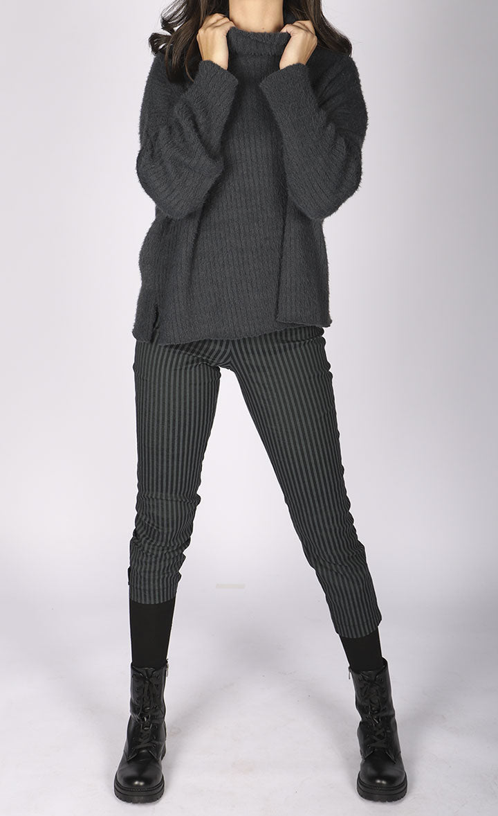 Front full body view of a woman wearing a grey sweater and the luukaa striped lycra pant. This slim pant has a cropped cut and grey and black vertical striping.