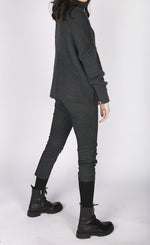 Load image into Gallery viewer, Right side full body view of a woman wearing a grey sweater and the luukaa striped lycra pant. This slim pant has a cropped cut and grey and black vertical striping.
