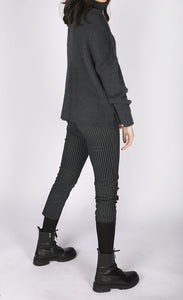 Right side full body view of a woman wearing a grey sweater and the luukaa striped lycra pant. This slim pant has a cropped cut and grey and black vertical striping.