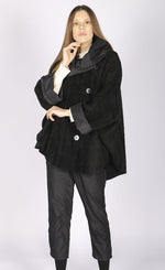 Load image into Gallery viewer, Front full body view of a woman wearing black pants and the luukaa black short coat. This coat is oversized with off center buttons running down the front, a wide collar, and fluffy looking black fabric.
