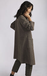 Load image into Gallery viewer, Right side full body view of a woman wearing brown cropped pants and the luukaa wrap coat/jacket. This jacket/coat is mink/dark brown with a shawl collar, two front pockets, and long sleeves.
