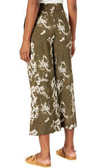Load image into Gallery viewer, back Bottom half view of a woman wearing the lysse lila crop pant. This pant is green/khaki with a tie dye tropical floral white print and wide legs.
