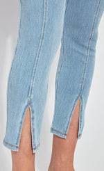 Load image into Gallery viewer, Front, close up view of a woman wearing the Lysse Evelyn Split Denim Leggings. These leggings are a light wash with seams running down the center and a small front slit at the bottom.
