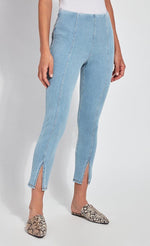 Load image into Gallery viewer, Front, bottom half view of a woman wearing the Lysse Evelyn Split Denim Leggings. These leggings are a light wash with seams running down the center and a small front slit at the bottom.
