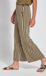 Load image into Gallery viewer, Left side bottom half view of a woman wearing the lysse clara pant. This pant has khaki and white stripes. It&#39;s wide legged with a flat front and 3 side buttons.
