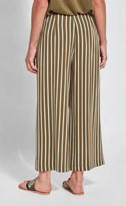 Back bottom half view of a woman wearing the lysse clara pant. This pant has khaki and white stripes. It's wide legged.