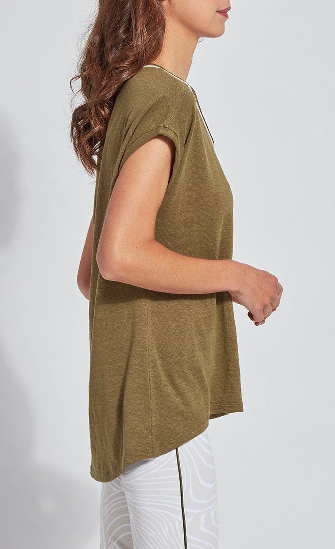 Right side top half view of a woman wearing the lysse classic tee. this tee is jungle khaki colored. It has short drop shoulder sleeves, a high low hem, and white edging around the round neck. 