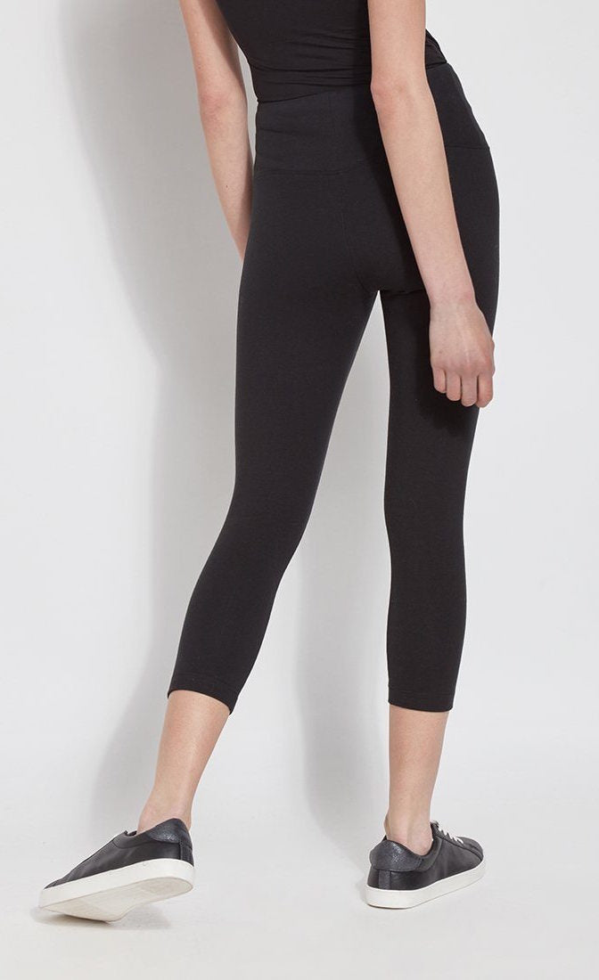 Back bottom half view of a woman wearing Lysse's Flattering Cotton Crop Legging. These leggings are black and have a high-rise, large waistband.