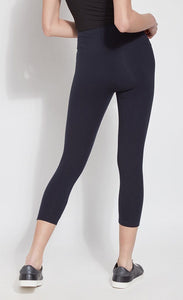 Back bottom half view of a woman wearing Lysse's Flattering Cotton Crop Legging. These leggings are navy and have a high-rise, large waistband.