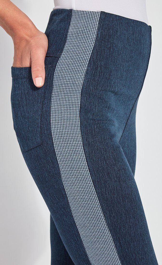 Right side, close up view of a woman wearing the Lysse Nomad Crop Leggings. These leggings are dark denim with a side blue and white houndstooth printed stripe going down the entire leg. The woman has her hands in the back pocket of the leggings.