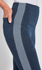 Load image into Gallery viewer, Right side, close up view of a woman wearing the Lysse Nomad Crop Leggings. These leggings are dark denim with a side blue and white houndstooth printed stripe going down the entire leg. The woman has her hands in the back pocket of the leggings.
