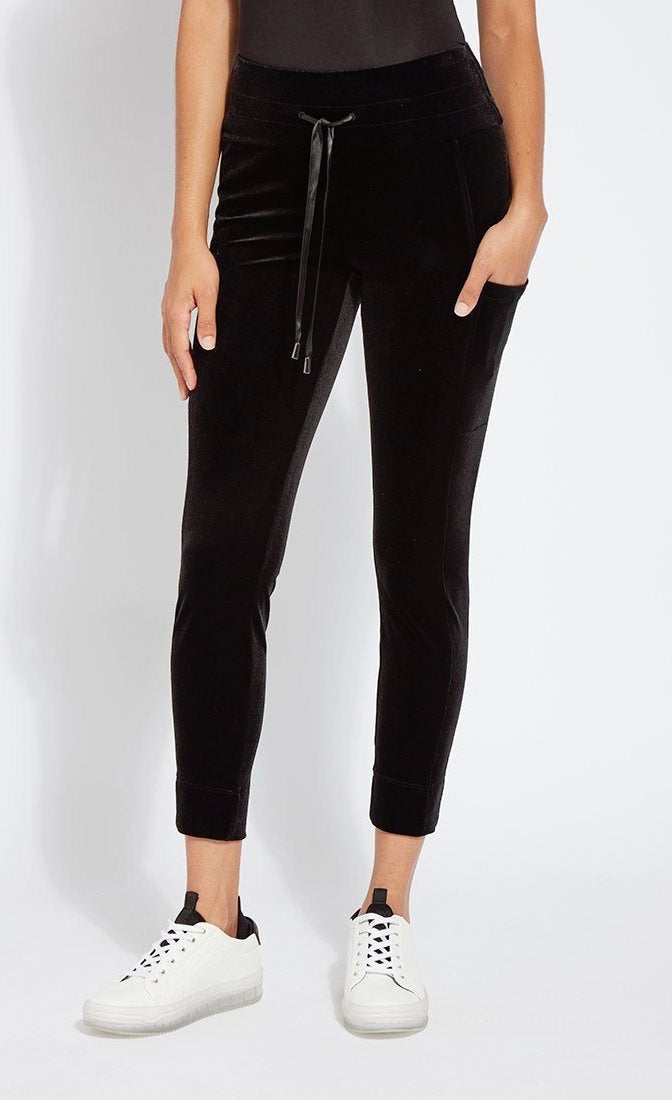 Front bottom half view of a woman wearing the lysse nook velvet jogger. This black jogger is body hugging like a legging with side pockets and a high-waisted tie waistband.