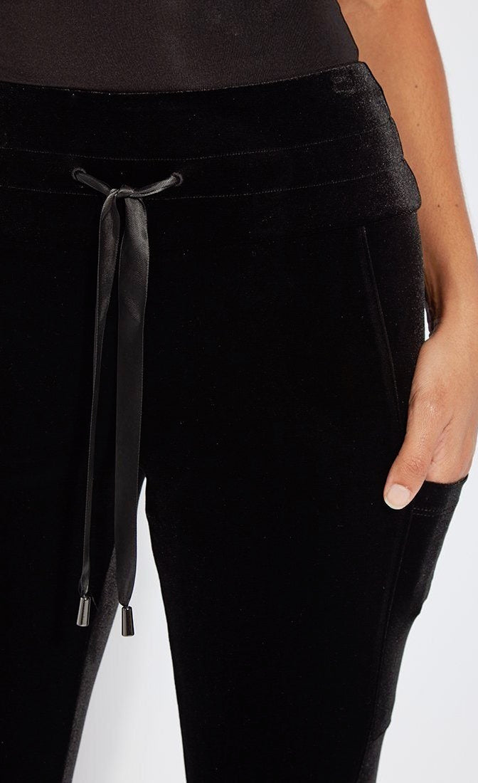 Close up view of a woman wearing the lysse nook velvet jogger. This black jogger is body hugging like a legging with side pockets and a high-waisted tie waistband.