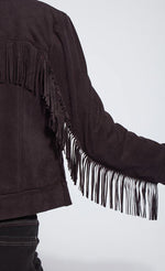 Load image into Gallery viewer, Back close up view of a woman wearing black pants and the black lysse spice fringe jacket. This jacket is suede looking and has fringe all along the arms and back.
