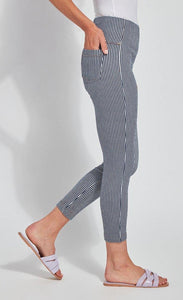 Right side bottom half view of a woman wearing the Lysse Toothpick Crop Pattern Legging with her hand in the back right pocket. These leggings are indigo and white pinstriped and high waisted and have two back pockets.