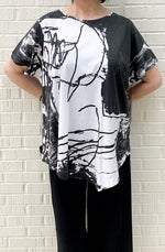 Load image into Gallery viewer, Front top half view of a woman wearing the moyuru short sleeve printed top. This top is white with black abstract print and an asymmetrical hem.

