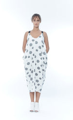 Load image into Gallery viewer, Front full body view of a woman wearing the m x matthildur trapeze dress. This dress is sleeveless with black elastic straps. This dress is white/ivory with black dots all over it. The front has two front pockets and a v-neck.
