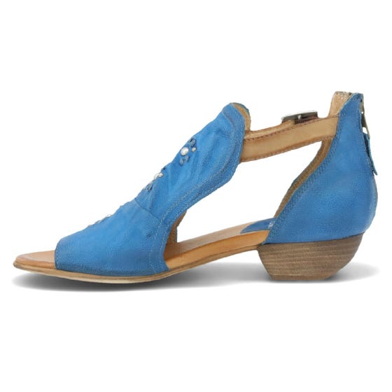 Inner side view of the miz mooz canary sandal in the color denim. This sandal has an open toe, a mid-heel, a buckle strap around the ankle, and exposed sides.