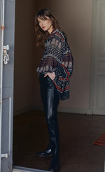 Load image into Gallery viewer, Front full body view of a woman wearing black leather pants and the molly bracken tzigane print shirt. This shirt has a mix of black, white, and red prints, a button down front, an oversized fit, and balloon sleeves.
