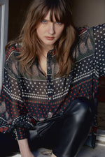 Load image into Gallery viewer, Front top half view of a woman wearing the molly bracken tzigane print shirt. This shirt has a mix of black, white, and red prints, a button down front, an oversized fit, and balloon sleeves.
