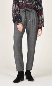 Front bottom half view of a woman wearing the molly bracken tzigane print shirt and the molly bracken grey herringbone pant. This pant has an elastic waistband with a black tie and a wider fit with legs that taper in at the bottom.