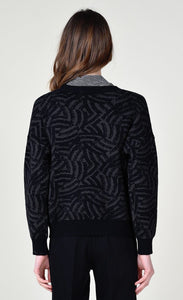 Back top half view of a woman wearing black pants and the molly bracken dark grey zebra sweater. This sweater is grey with black zebra print. It has long sleeves with black cuffs and a relaxed fit.