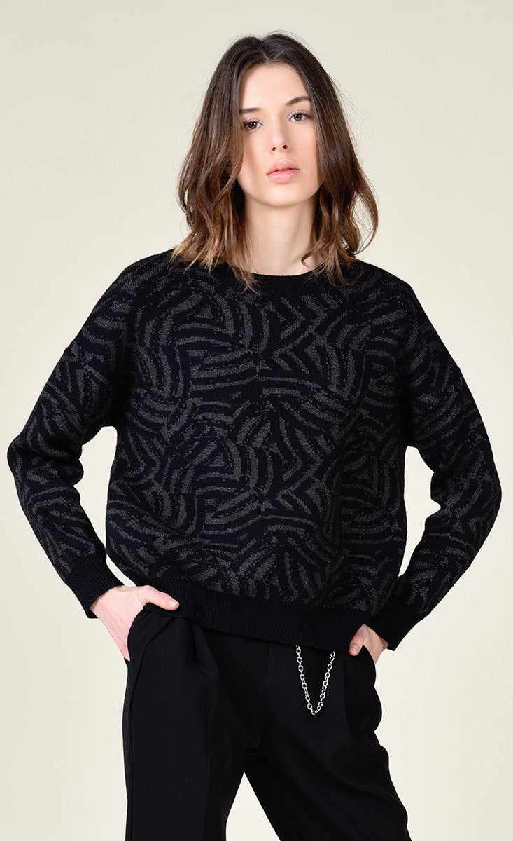 Front top half view of a woman wearing black pants and the molly bracken dark grey zebra sweater. This sweater is grey with black zebra print. It has long sleeves with black cuffs and a relaxed fit.